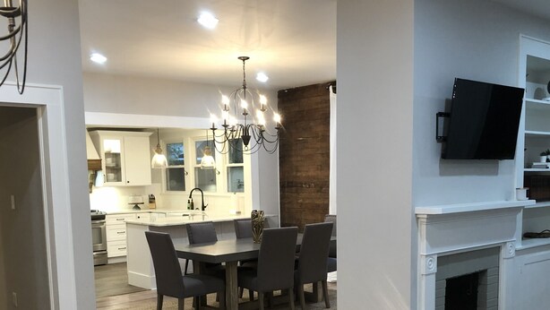 A modern kitchen with white cabinets, a central island, and a chandelier. - Jacklin Cottage at Generals' Quarters (Corinth)