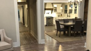 A modern kitchen with a dining area, wooden flooring, and a chandelier. - Jacklin Cottage at Generals' Quarters (Corinth)