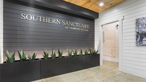 A reception area with a sign reading "Southern Sanctuary at Cranford Hollow," a planter with green plants, and a wooden door.