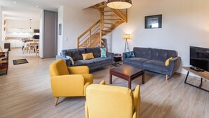 Un salon moderne avec un escalier, un coin repas et un téléviseur.