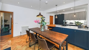 Une cuisine moderne avec des meubles en bois, une table à manger avec des chaises et des luminaires suspendus.