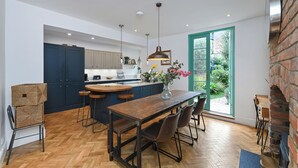 Une cuisine moderne avec des meubles de couleur bleu foncé, une table à manger en bois et une grande fenêtre.