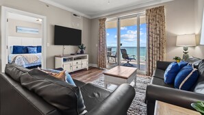 Un salon comprenant un canapé, une table basse, un téléviseur et un balcon avec vue sur la mer.