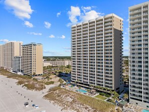 Ein Hochhaus-Hotel mit mehreren Balkonen, einem Schwimmbad und einer Strandanlage.