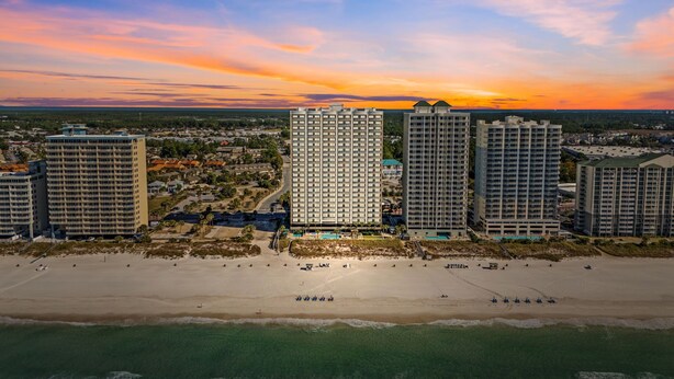 Un paysage urbain côtier avec de hauts immeubles, une plage et un coucher de soleil.