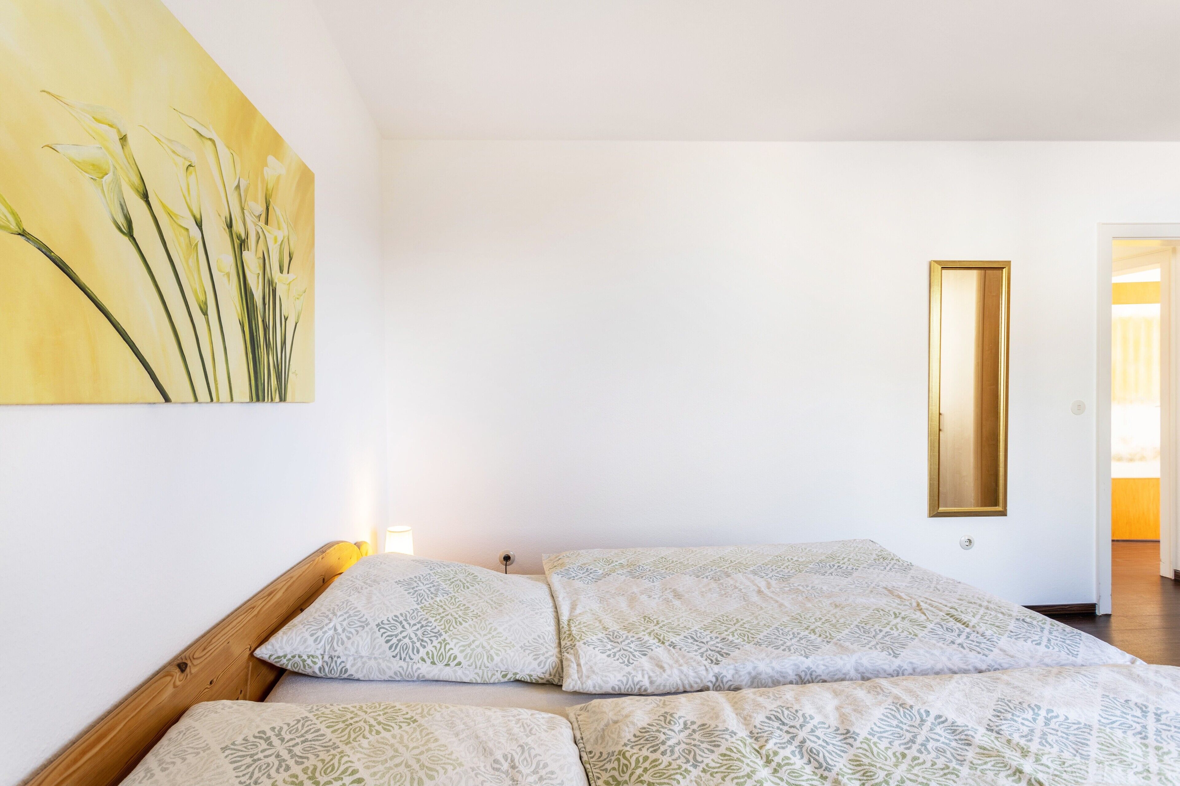 Un dormitorio con una cama, almohadas estampadas, un cuadro en la pared y un espejo.
