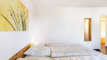 Un dormitorio con una cama, almohadas estampadas, un cuadro en la pared y un espejo.