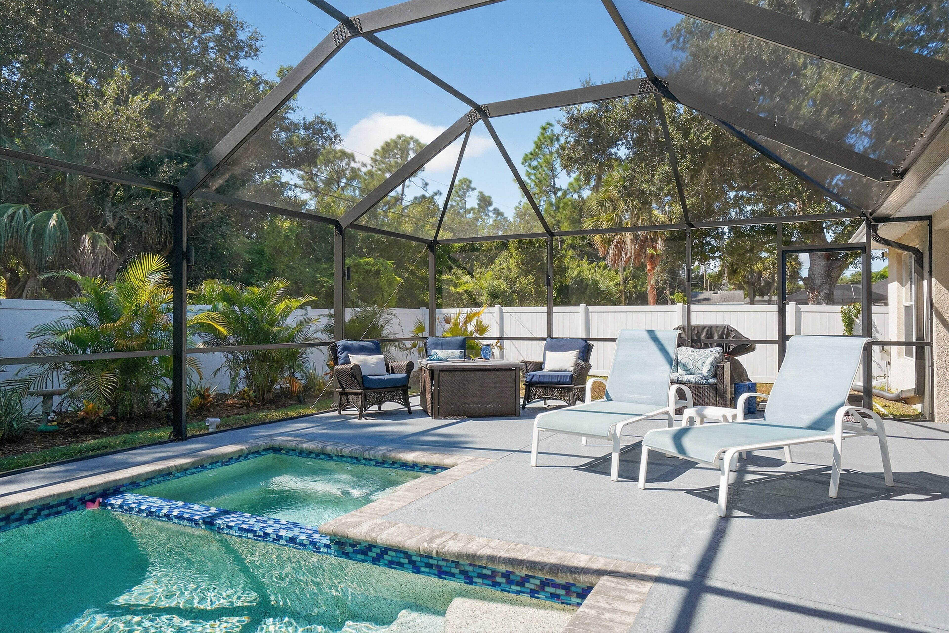 Espaço ao ar livre coberto com piscina, espreguiçadeiras e uma mesa.