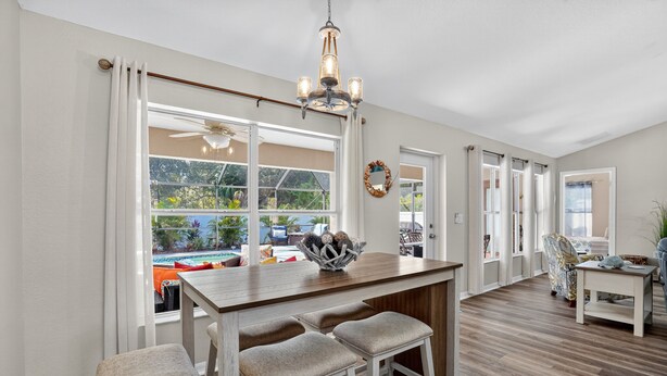 A spacious kitchen with a wooden island, bar stools, and a view of a swimming pool.
