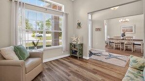A spacious living room with a large window, a dining area, and a cozy seating area.