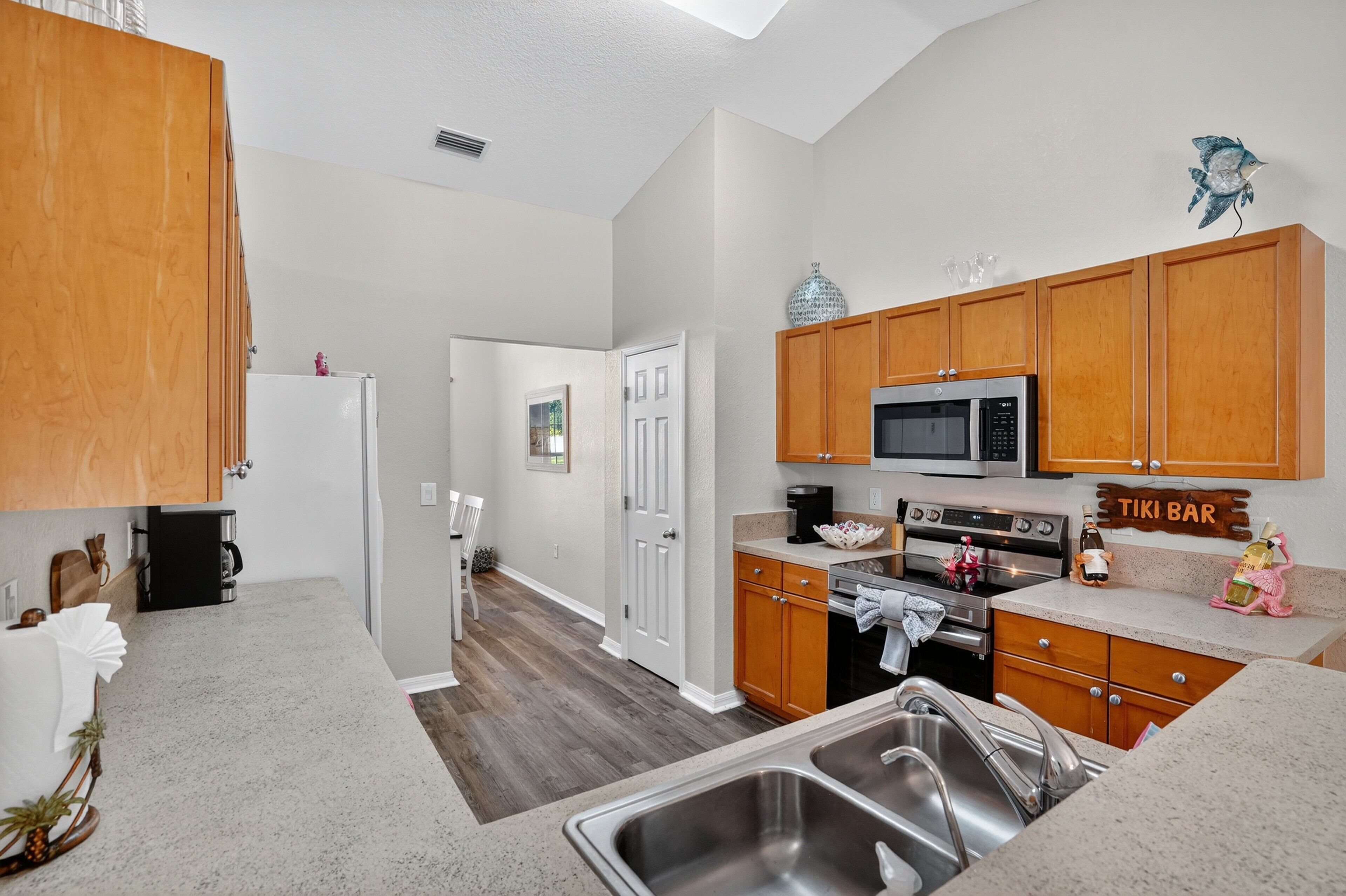 A kitchen with wooden cabinets, a stainless steel sink, a microwave, and a stove.
