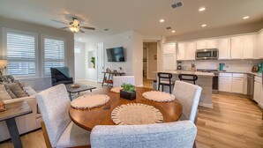 A modern living room with a wooden dining table, grey upholstered chairs, and a ceiling fan. - Ot 2125 Creekside Cottage 2 Bedroom Home (New Braunfels)