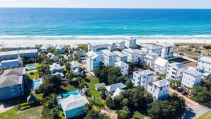 A coastal residential area with modern buildings, a swimming pool, and a view of the ocean. - Blue Palm 3 Bedroom Home (Panama City Beach)
