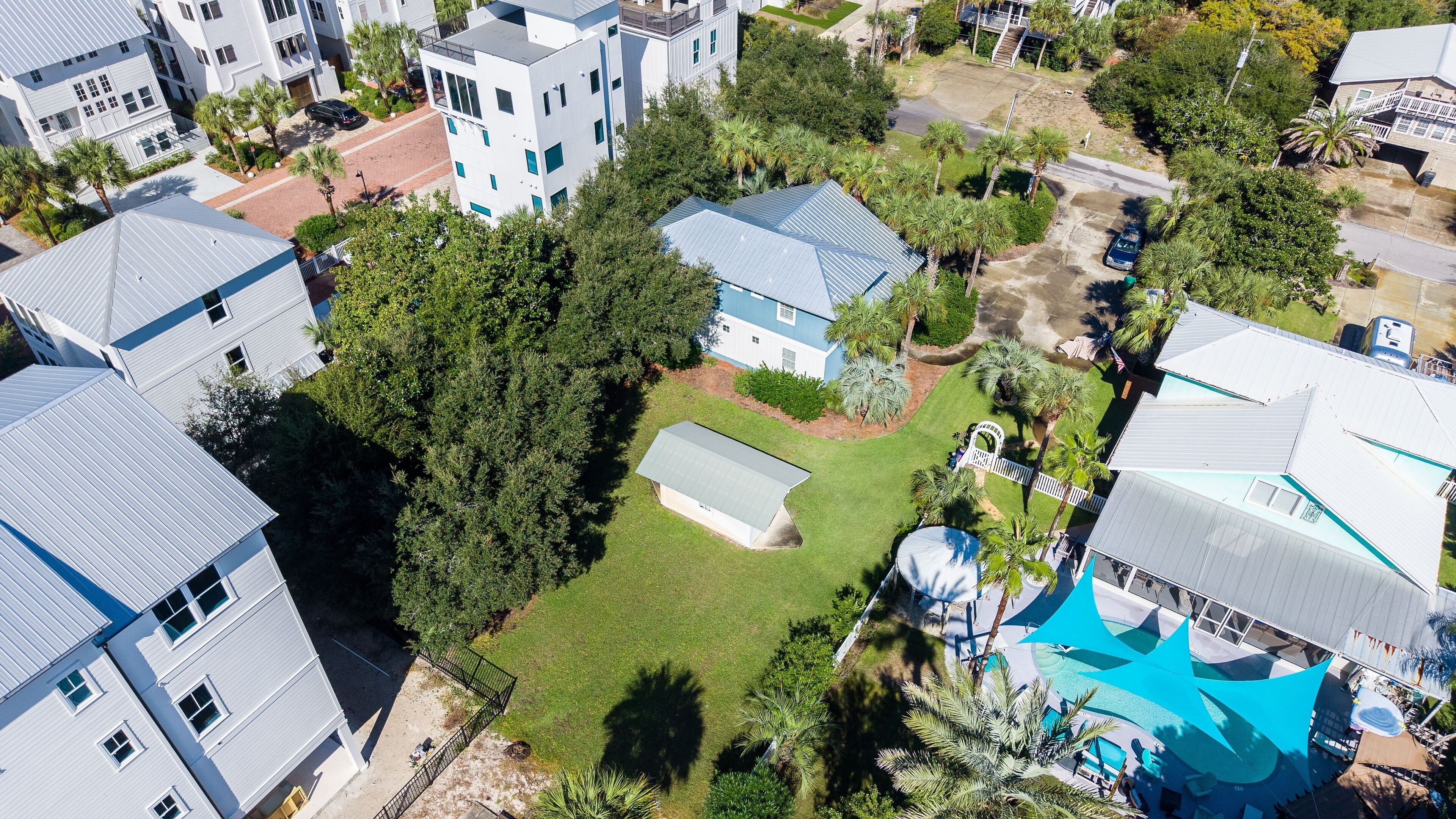 An aerial view of a residential area with multiple houses, a swimming pool, and a fenced yard.