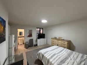 A bedroom with a bed, dresser, television, and artwork on the wall.