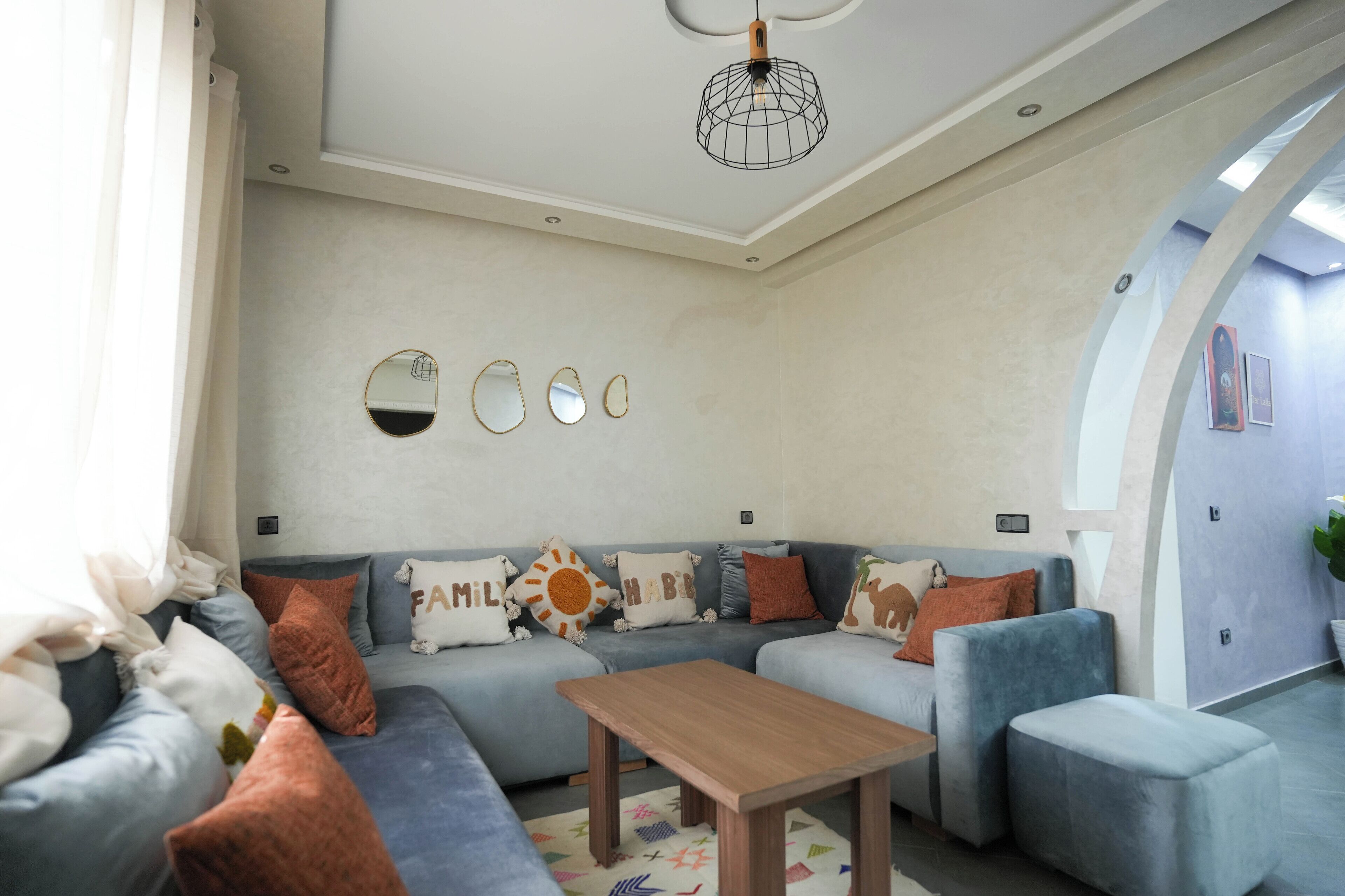 A modern living room with a sectional sofa, a wooden coffee table, and a ceiling light fixture.