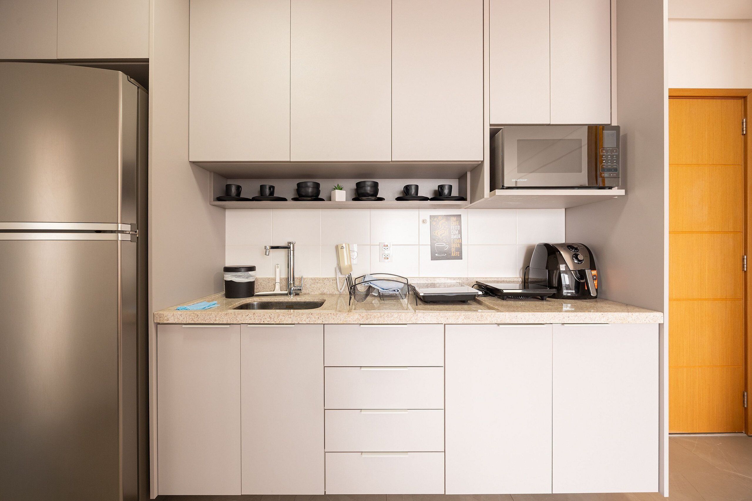 Una cocina moderna con un refrigerador de acero inoxidable, un microondas y una cafetera.