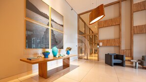 A modern lobby with a reception desk, seating area, and large windows. - Apartamento Moderno Premium - Cittyplex  (Osasco)