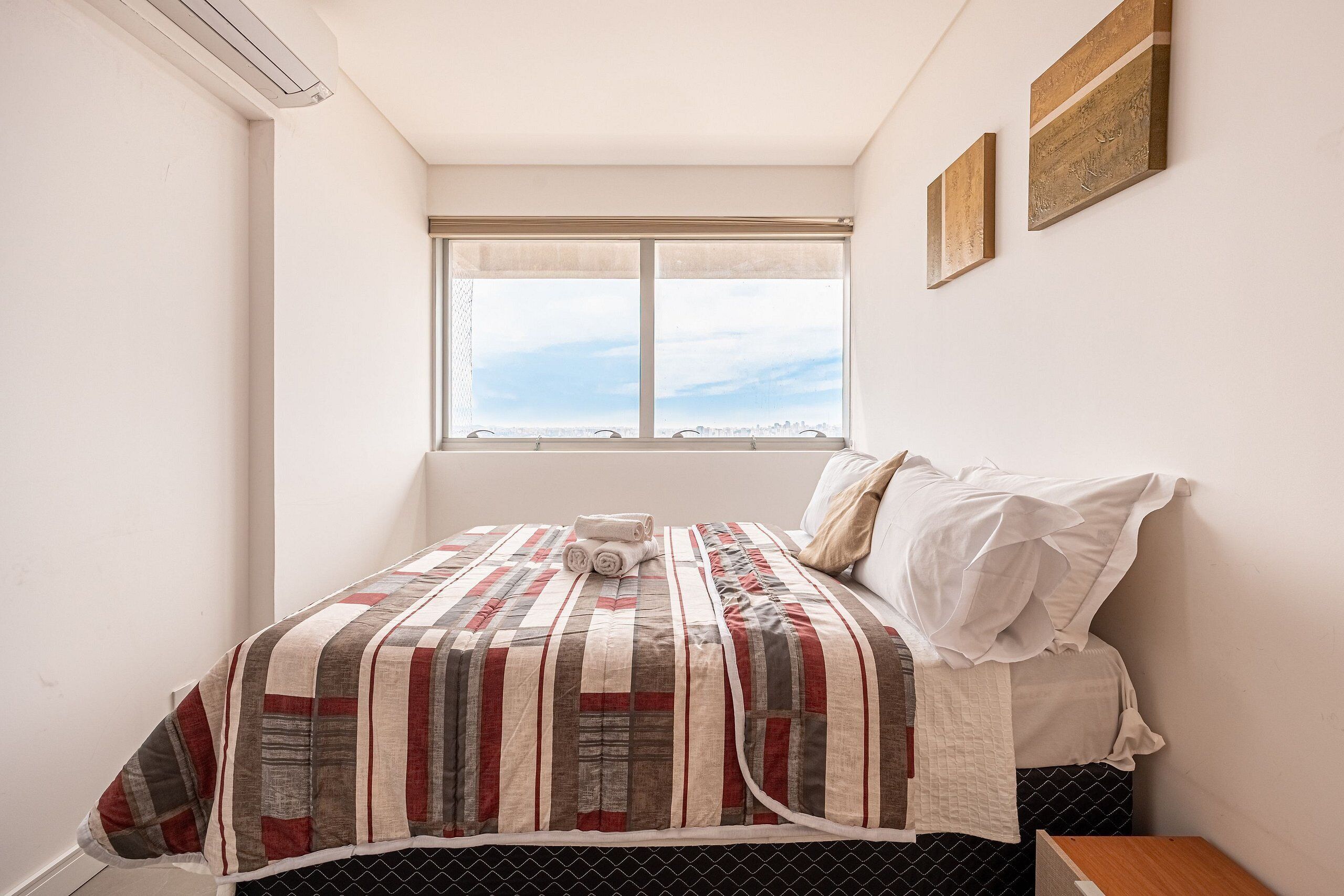 Ein Schlafzimmer mit einem Bett, einem Fenster und zwei Wandbildern.