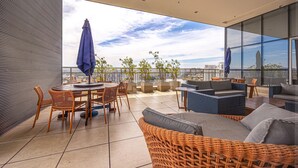 A modern outdoor patio with wicker furniture, a round table, and potted plants. - Apartamento Moderno Premium - Cittyplex  (Osasco)