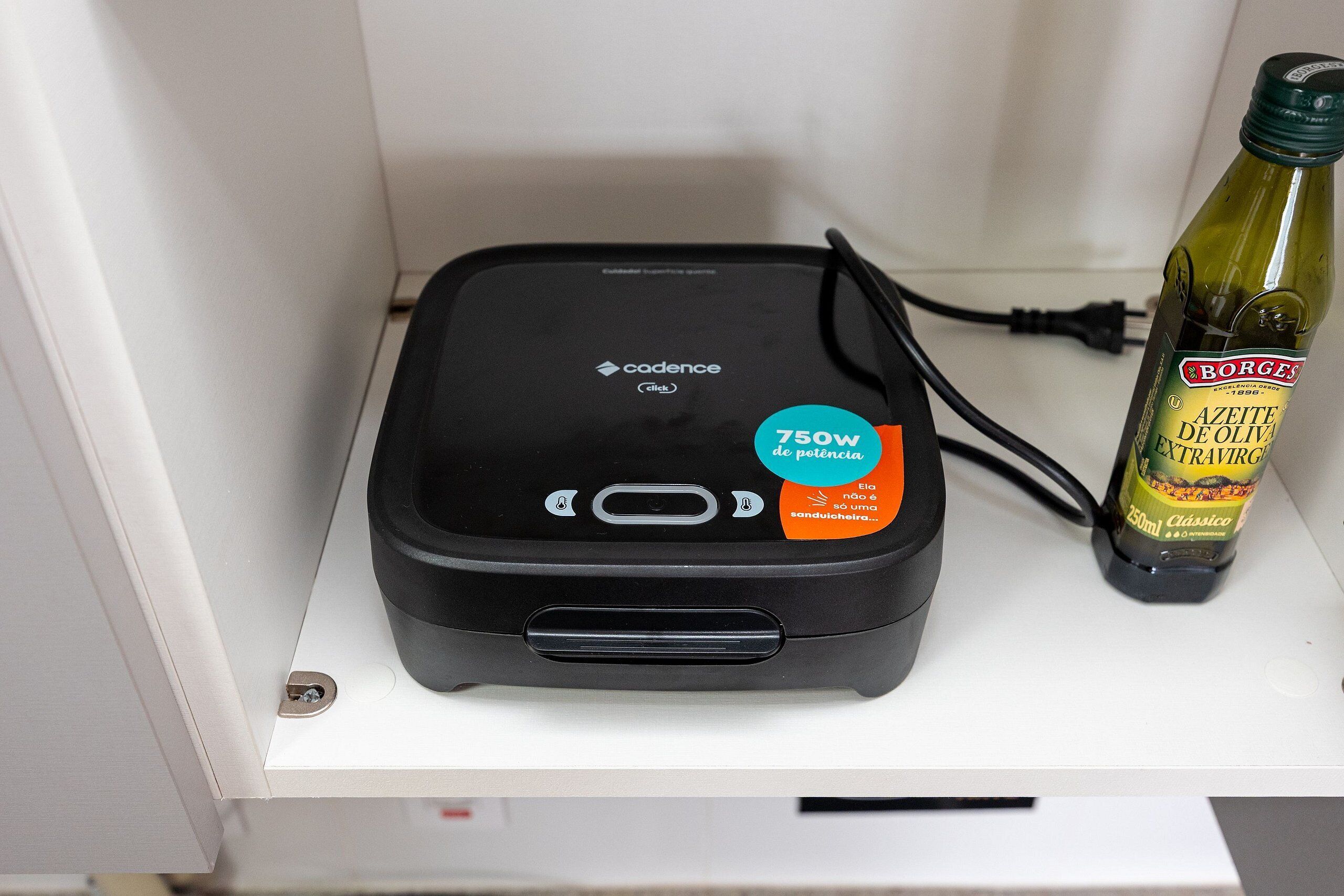 Une batterie externe noire, portable, avec une capacité de charge de 750 W, posée à côté d’une bouteille d’huile d’olive.