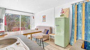 Un salon moderne avec un canapé, une table à manger et un réfrigérateur vert.