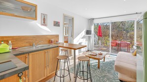 Une cuisine moderne avec des meubles en bois, un tabouret de bar et une grande fenêtre.