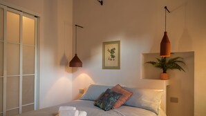 A bedroom with a bed, bedside lamps, a potted plant, and a framed picture on the wall. - La Voliera di Bacco - House with panoramic terrace in the heart of Frascati (Frascati)