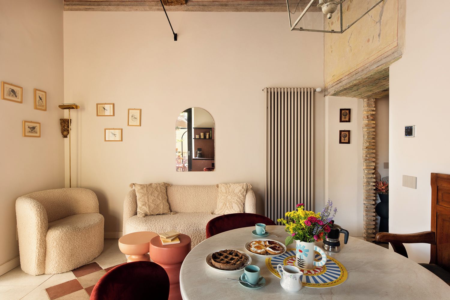 Ein gemütliches Wohnzimmer mit einer Couch, einem Esstisch mit Tellern und Tassen sowie einem Spiegel an der Wand.