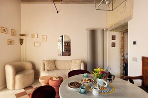 A cozy living room with a sofa, a dining table set with plates and cups, and a mirror on the wall.