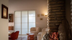 A living room with a checkered floor, a sliding glass door, and a stone wall. - La Voliera di Bacco - House with panoramic terrace in the heart of Frascati (Frascati)