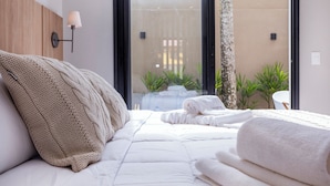 A bedroom with a bed, a wall-mounted lamp, and a view of the outside. - Solena Hotel (São Sebastião)