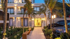 A hotel entrance with a pathway, palm trees, and a well-lit building facade. - Solena Hotel (São Sebastião)