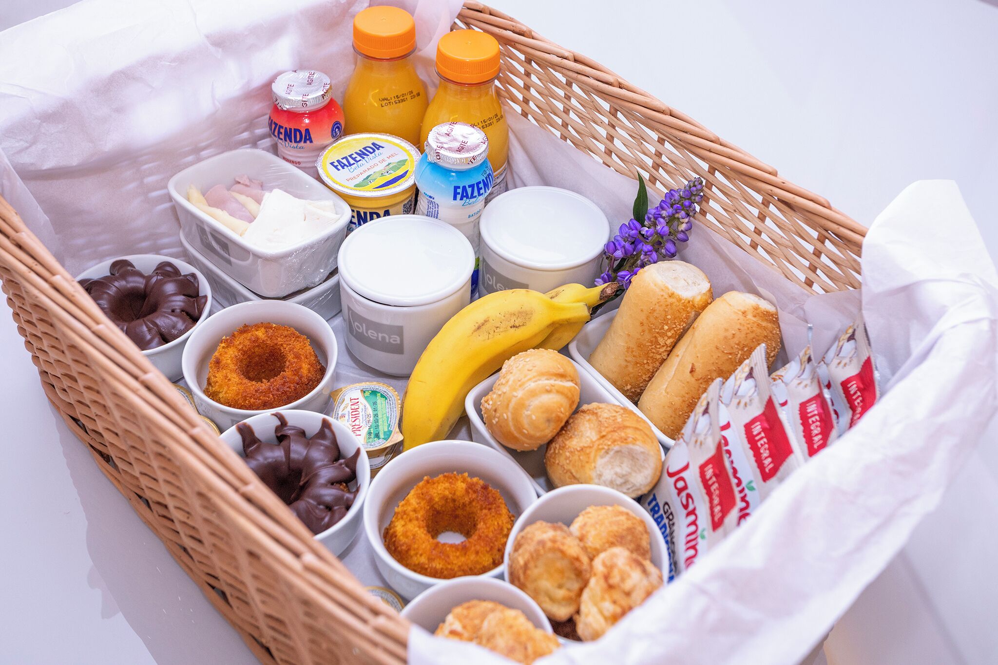 A wicker basket filled with various food items including pastries, a banana, and condiments.