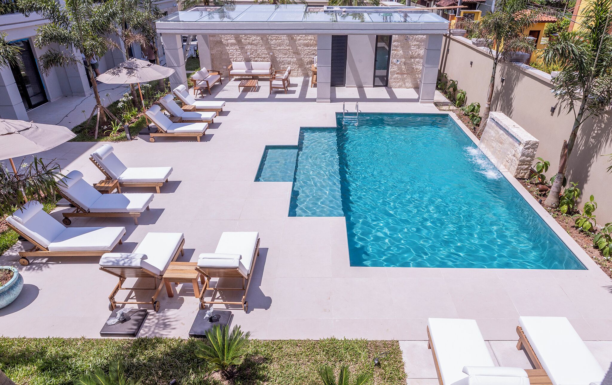 A rooftop pool area with multiple sun loungers and a clear blue pool.