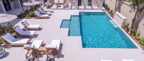 A rooftop pool area with multiple sun loungers and a clear blue pool.