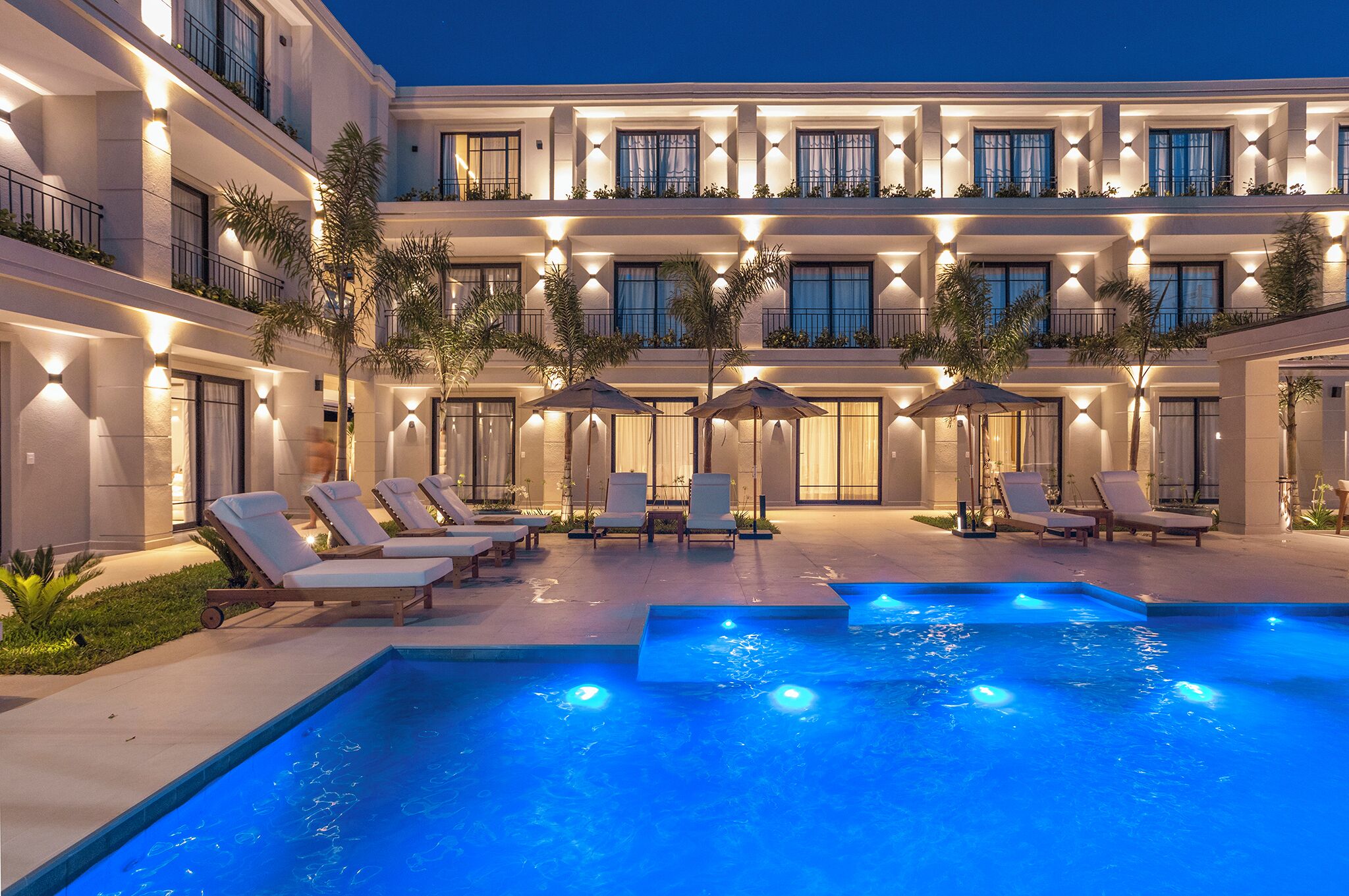 A hotel courtyard with a swimming pool, sun loungers, and umbrellas. - Solena Hotel (São Sebastião)
