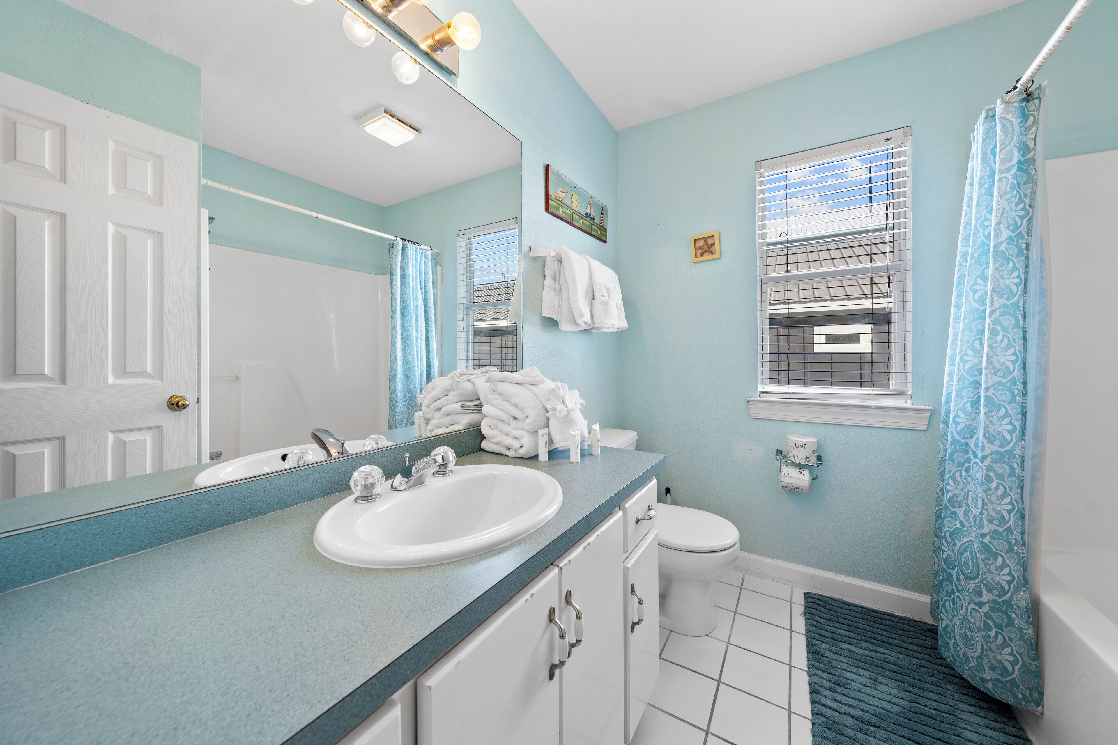 A bathroom with a white sink, a mirror, a toilet, and a shower curtain.