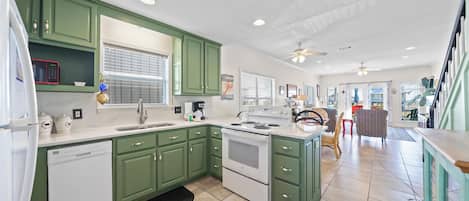 A kitchen with green cabinets, a dishwasher, a stove, and a sink.