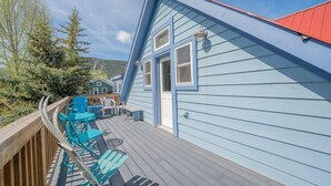 A blue house with a red roof, a deck with blue chairs, and a wooden railing. - Townhome in Crested Butte | 3 Bedroom | Walk to Elk Ave | Gas Grill | Parking (Crested Butte)