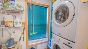 A laundry room with a washing machine, shelves with cleaning supplies, a window with blinds, and a mop. - Townhome in Crested Butte | 3 Bedroom | Walk to Elk Ave | Gas Grill | Parking (Crested Butte)