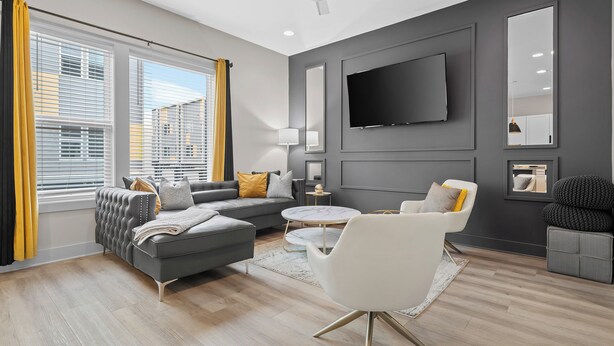 A modern living room with a grey sofa, white armchair, and a round coffee table. - NEW! Sleeps 20+ 2 SideBySide East Nashville Homes! (Nashville)