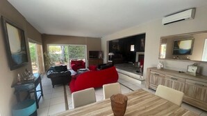 Ein geräumiger Wohnbereich mit Esstisch, rotem Sofa und einer Küche im Hintergrund.