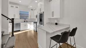 A modern kitchen with white cabinetry, a stainless steel refrigerator, and a wooden floor. - Eden Townhouse: Hot Tub & Golf Retreat w/Mountain Views (Eden)