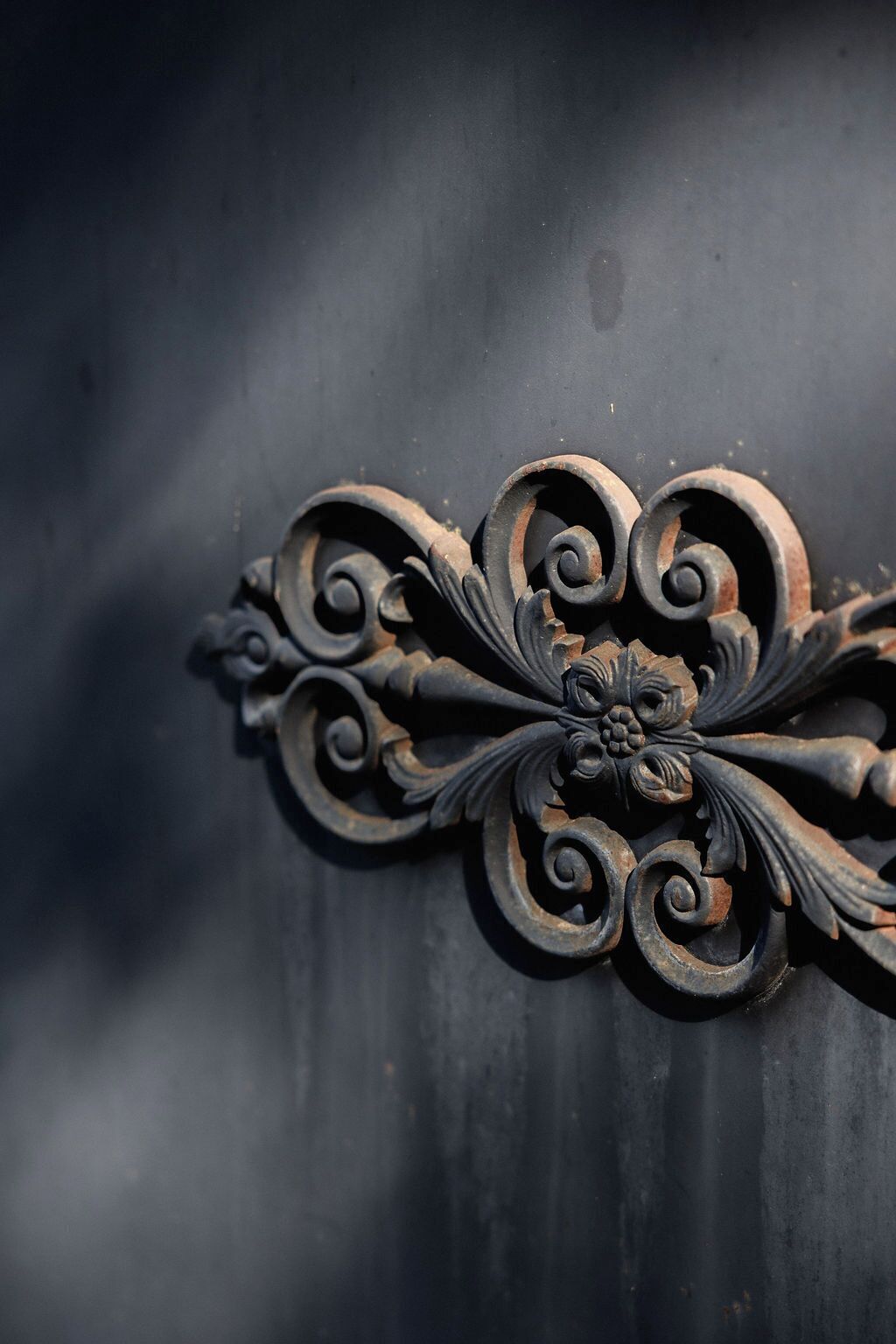 A close-up of an ornate metal door knocker with intricate scrollwork and a floral design.