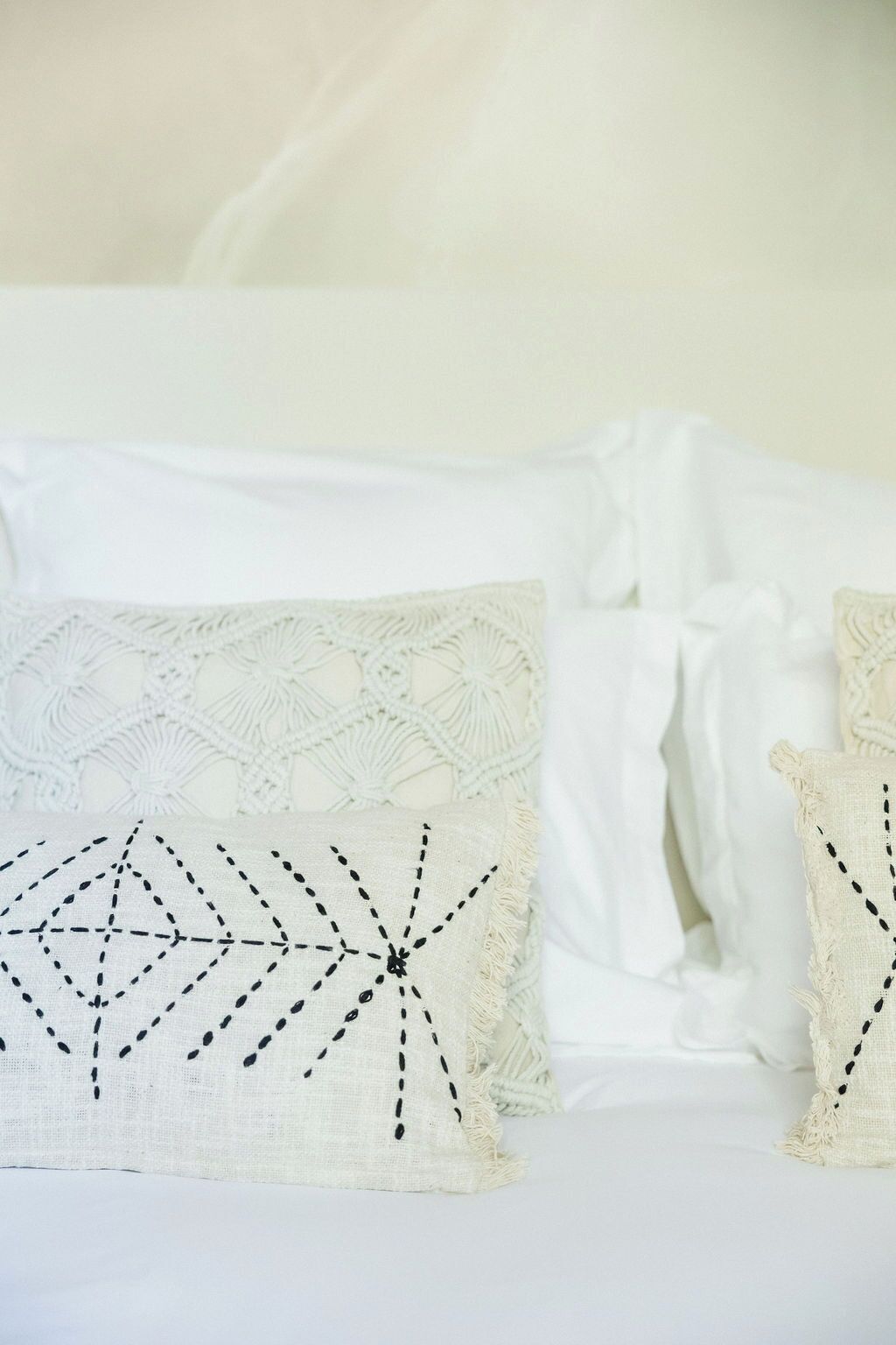 A bed with white bedding and decorative pillows with geometric patterns.