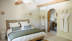 Una camera da letto con un letto, comodini, un appendiabiti a parete e una trave in legno al soffitto.