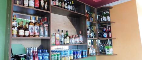 A bar area with shelves stocked with various alcoholic beverages and cans of energy drinks.