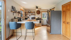 Una cocina moderna con una isla central, taburetes de bar, un refrigerador y un microondas.