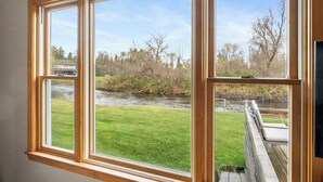 Una habitación con un ventanal grande que da a un río y una zona verde.